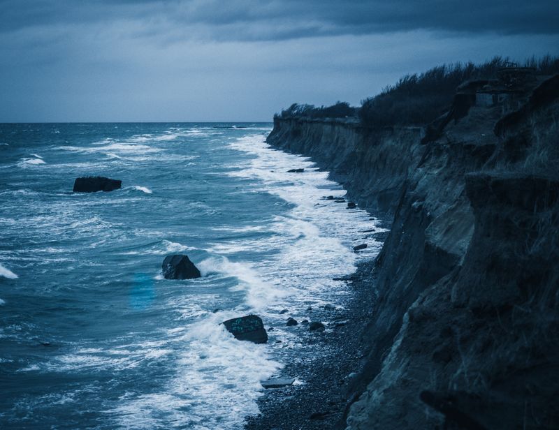 Dark ocean waves breaking under coastal cliffs — photo by Phil S on Pexels