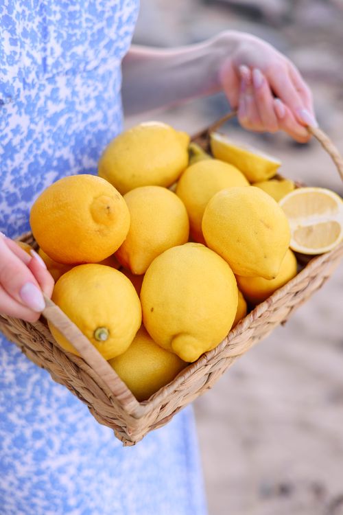 Free A basket of ripe, vibrant lemons held outdoors, perfect for cooking and health. Stock Photo