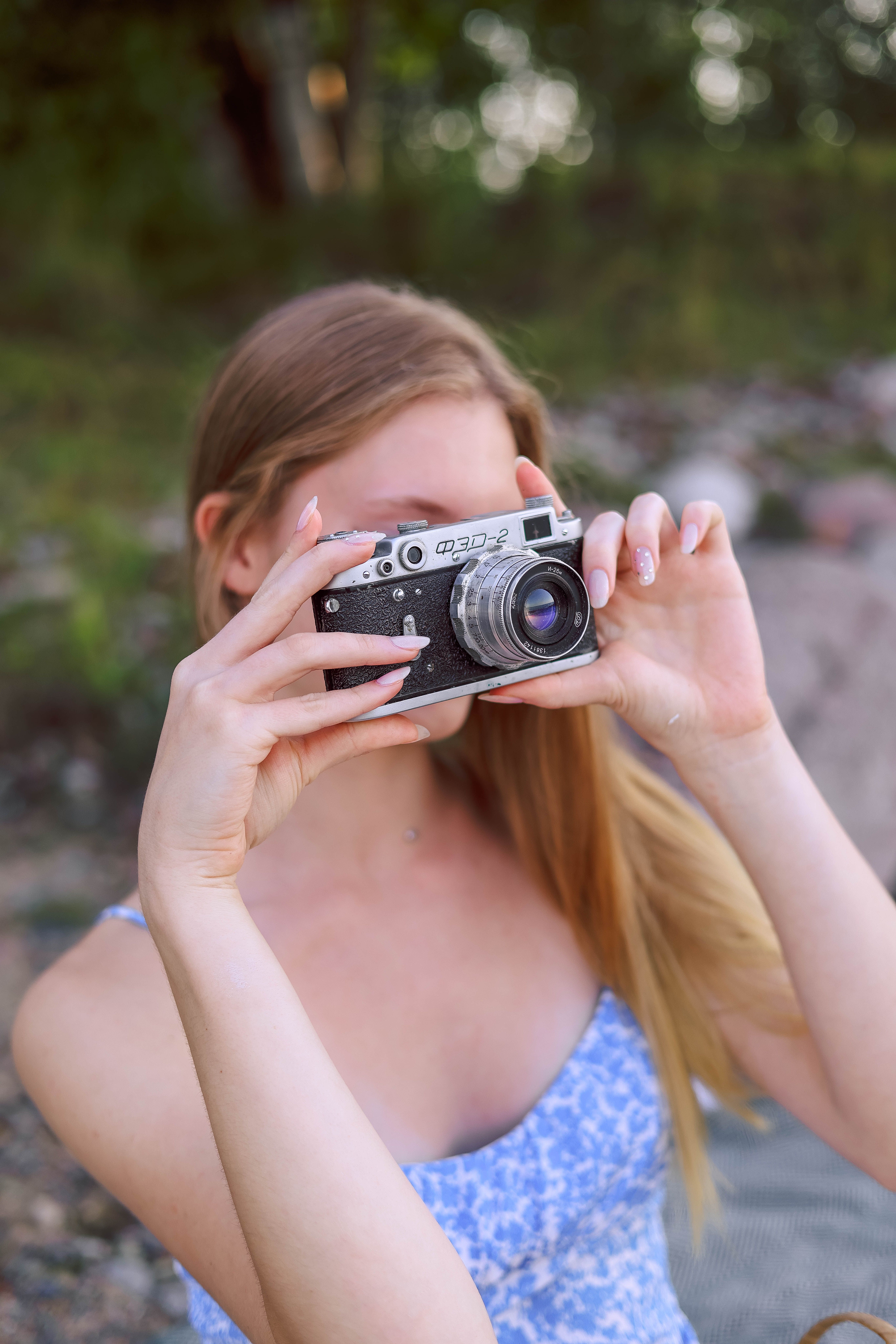 Young woman taking photos outdoors with a vintage camera.