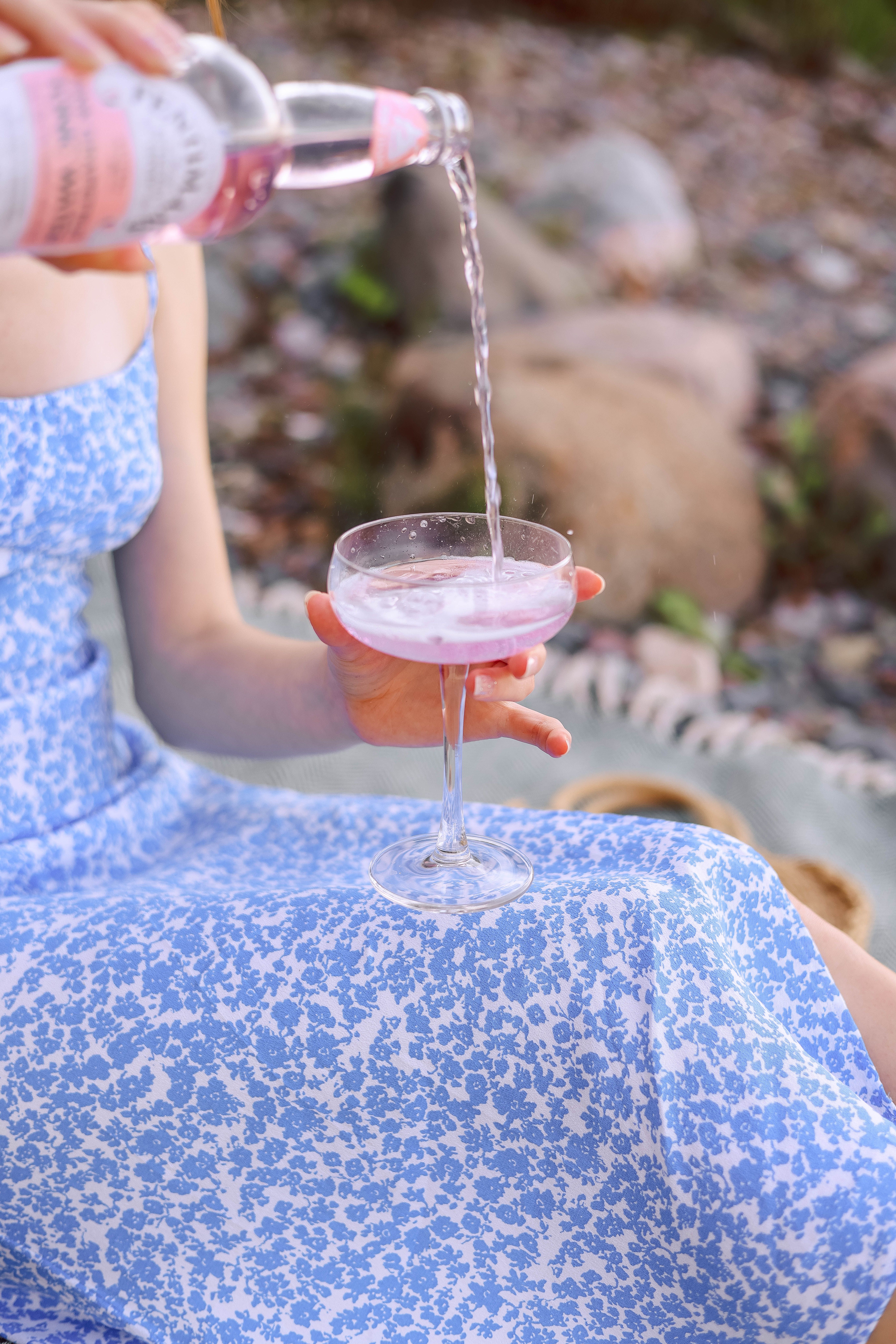 A refreshing pink drink being poured into a glass outdoors, capturing a summer vibe.