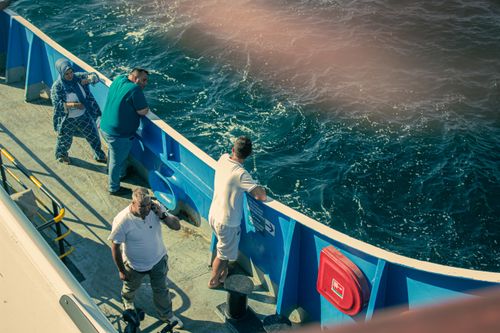 Free Adults enjoying a ferry ride in Çanakkale, Türkiye, with the ocean in view. Stock Photo
