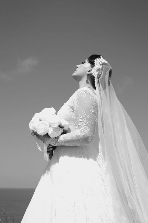 Free A bride in a lace dress holding a bouquet, captured in an elegant outdoor portrait. Stock Photo