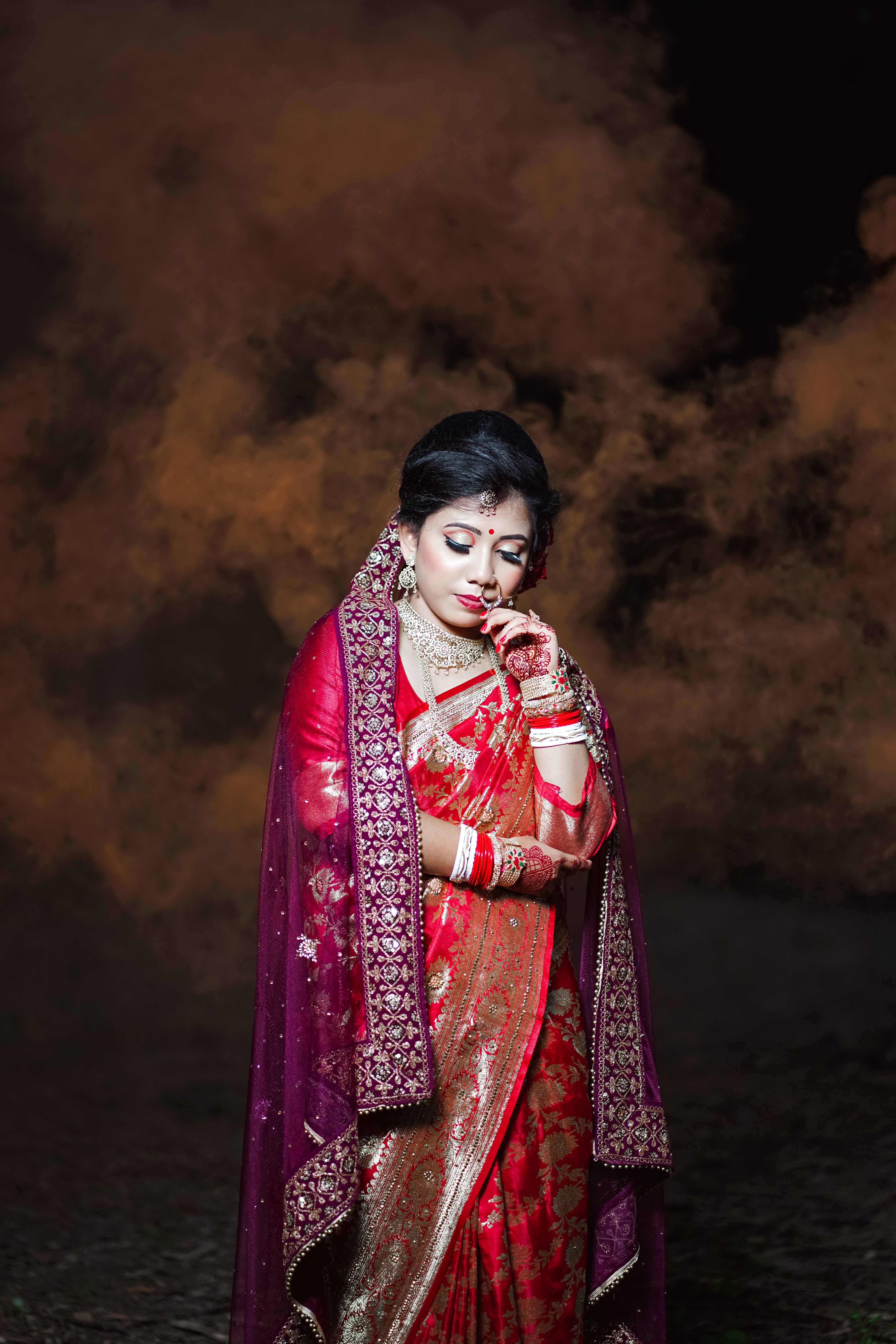 A woman in red and gold sari standing in smoke · Free Stock Photo