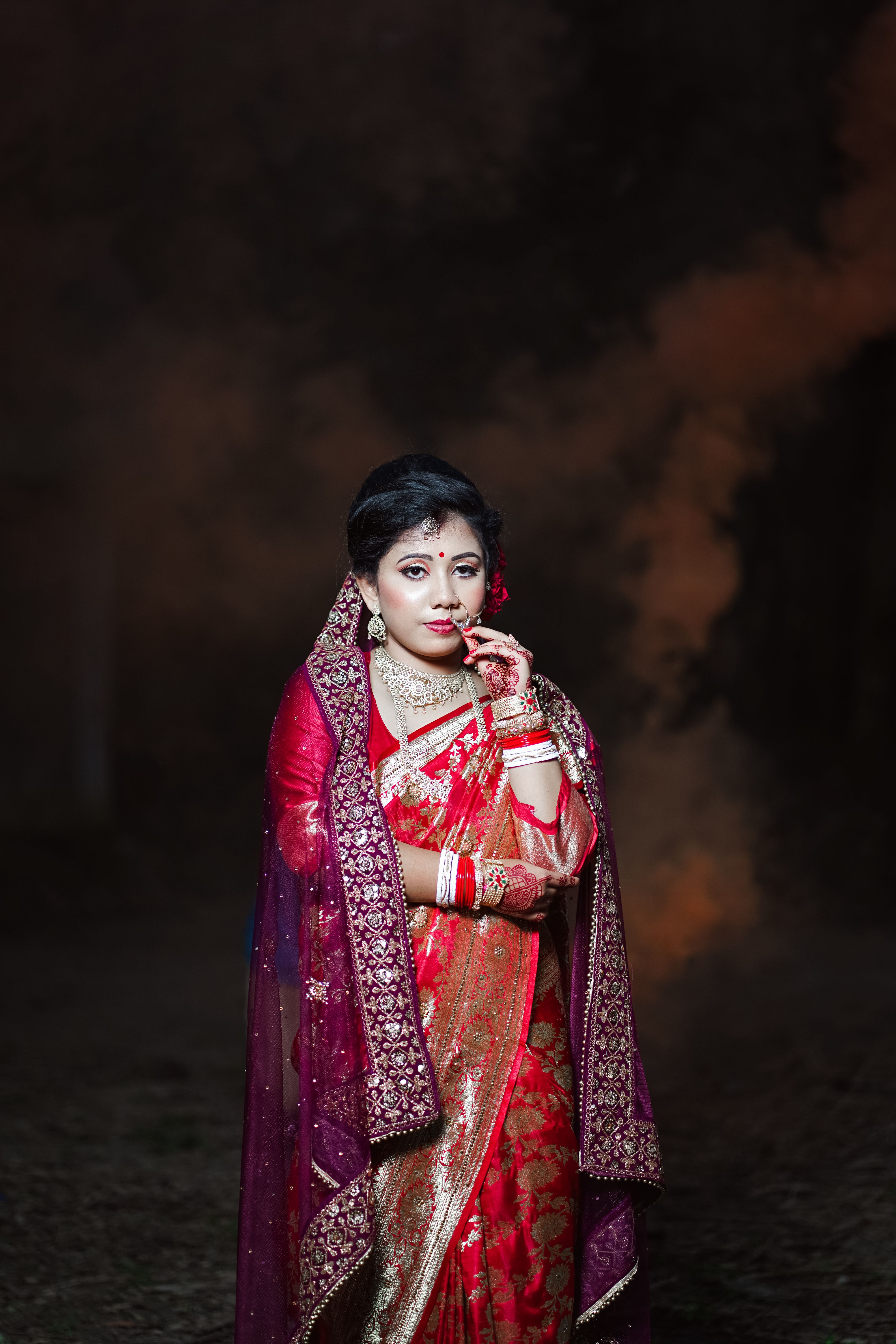 A woman in red and gold sari standing in front of smoke · Free Stock Photo