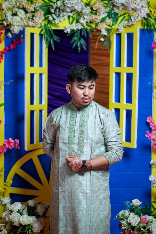Free Man in traditional Indian attire amidst colorful floral decor at a festive ceremony. Stock Photo