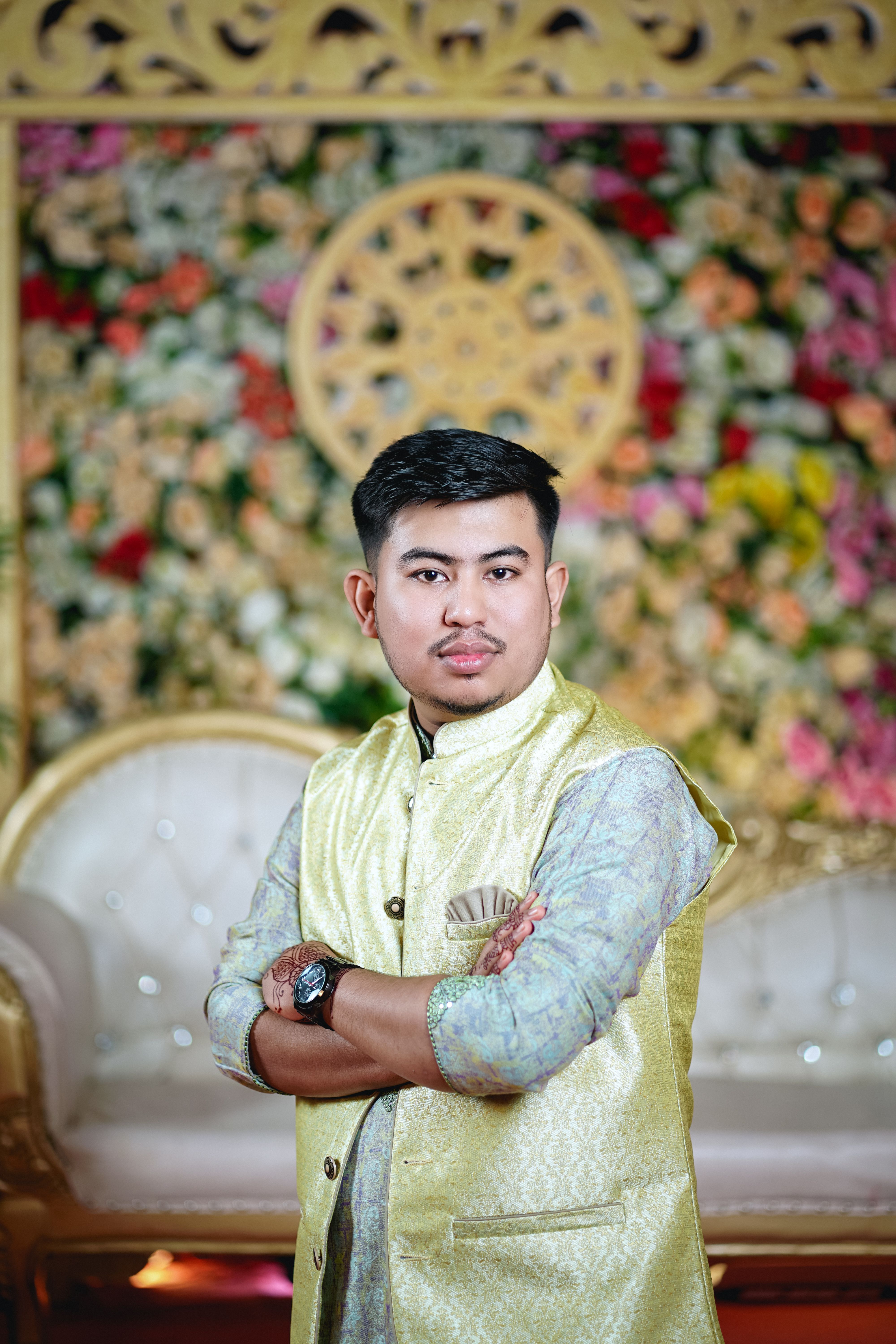A man in a gold vest standing in front of a floral wall · Free Stock Photo