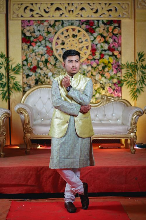 Free Man in traditional Indian wedding attire posing indoors with floral backdrop. Stock Photo
