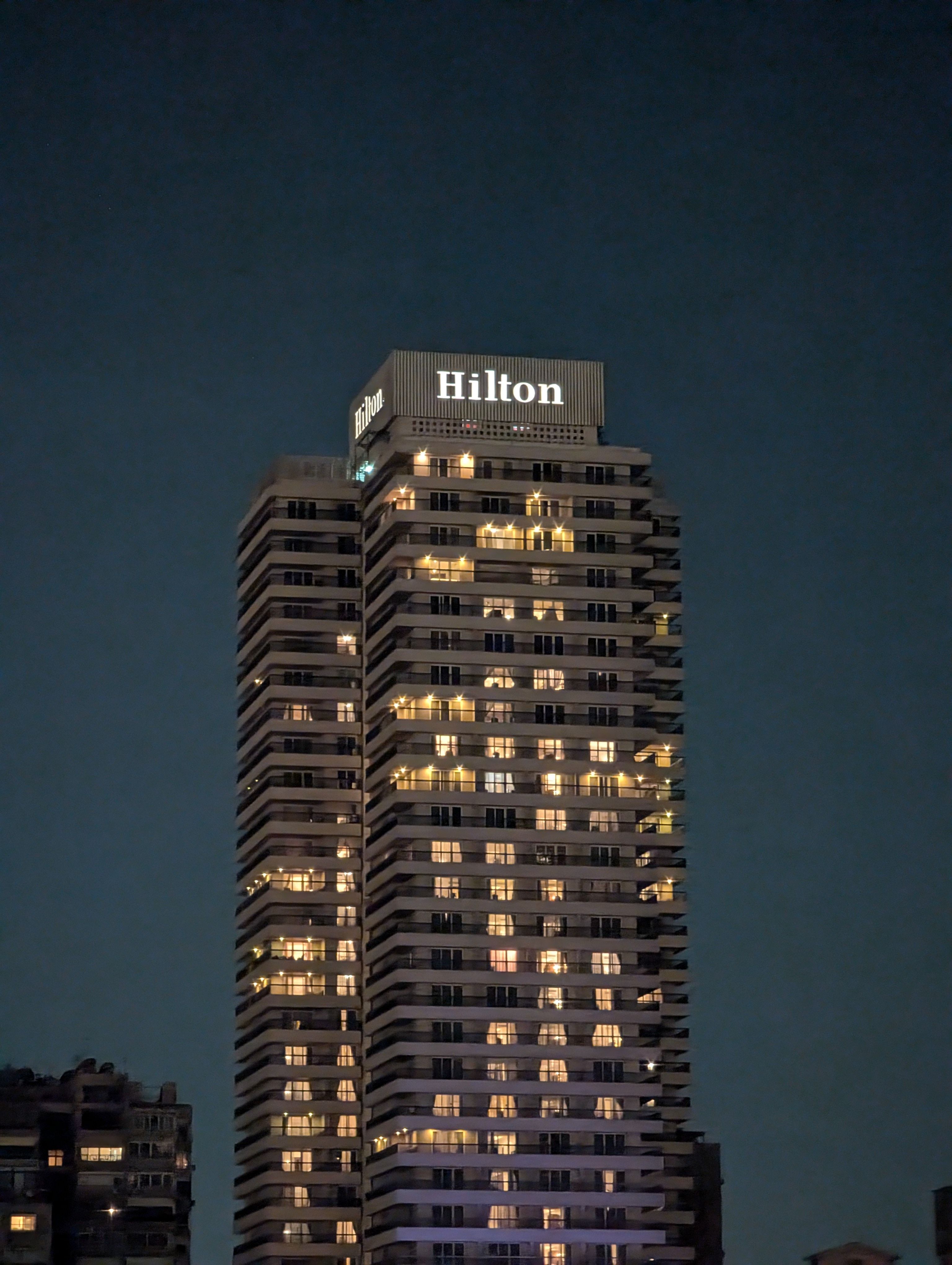 Modern hotel building lit up at night in a downtown host city