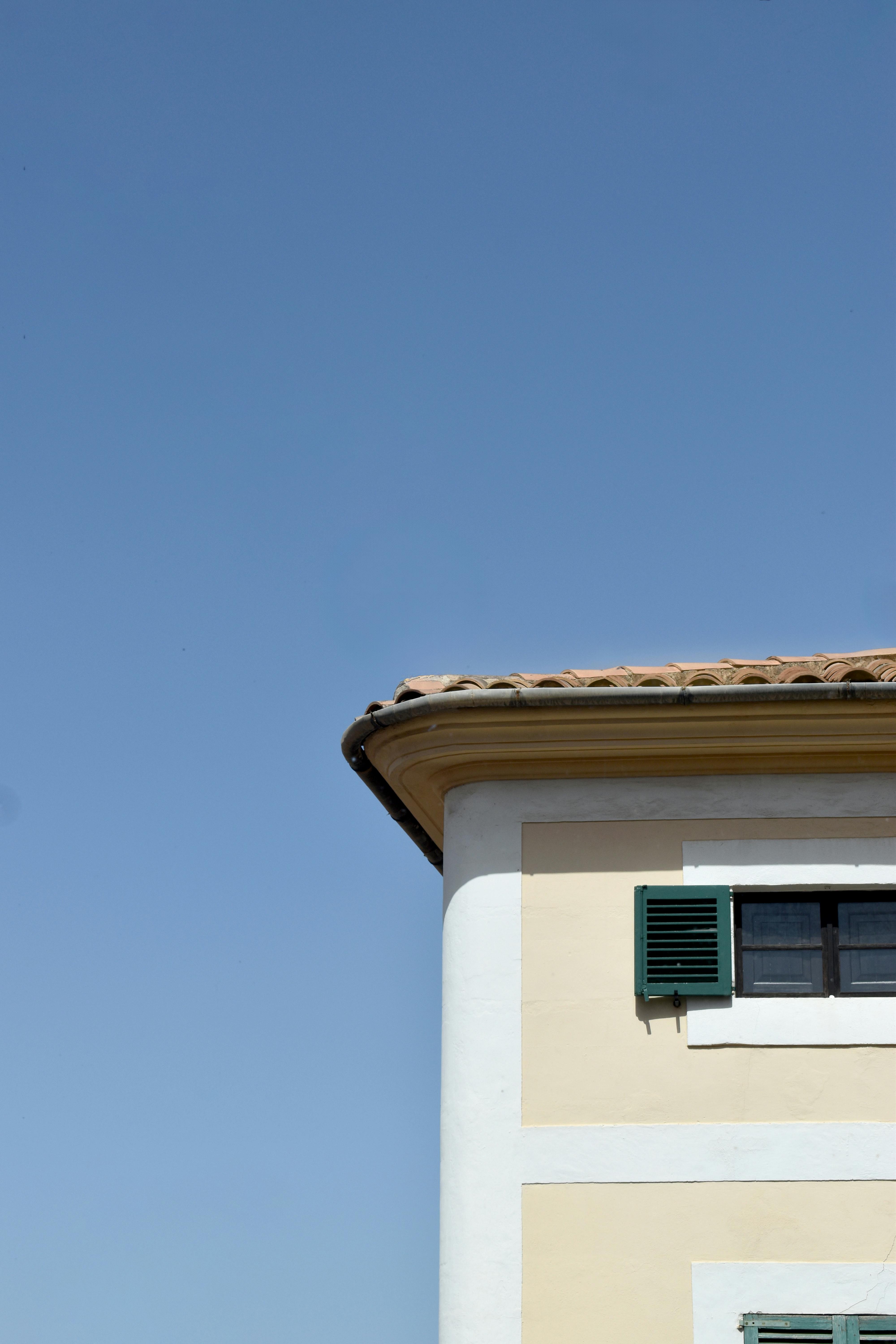Free A classic house exterior with blue sky and green shutters, ideal for travel. Stock Photo