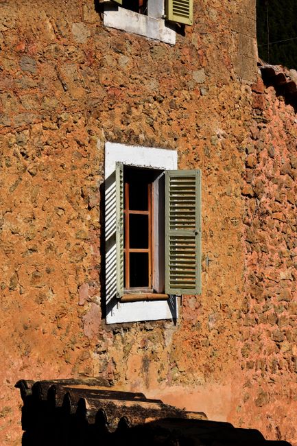 Close-up of a vintage-style rural house wall with an open shuttered window, highlighting rustic architecture.