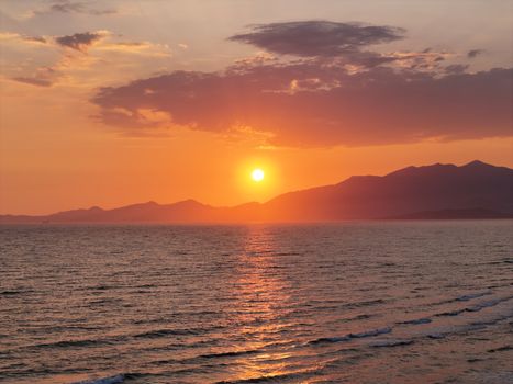 Beautiful sunset over the sea at Baia Domizia, Italy, with mountains and vibrant sky reflections.