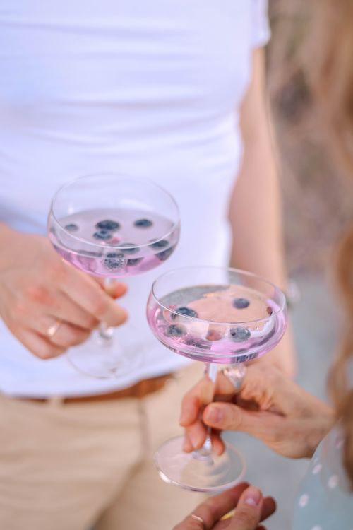 Free Cheers with pink cocktails garnished with blueberries, perfect for a summer celebration. Stock Photo