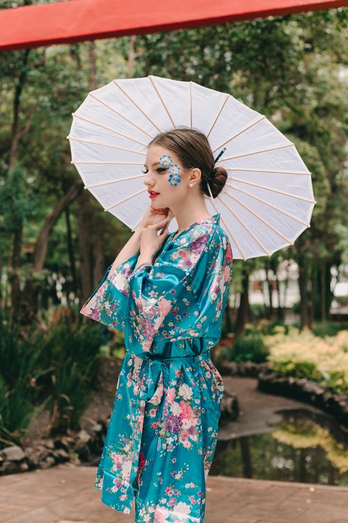 Free A young woman in a floral kimono relaxes outdoors with an umbrella. Stock Photo