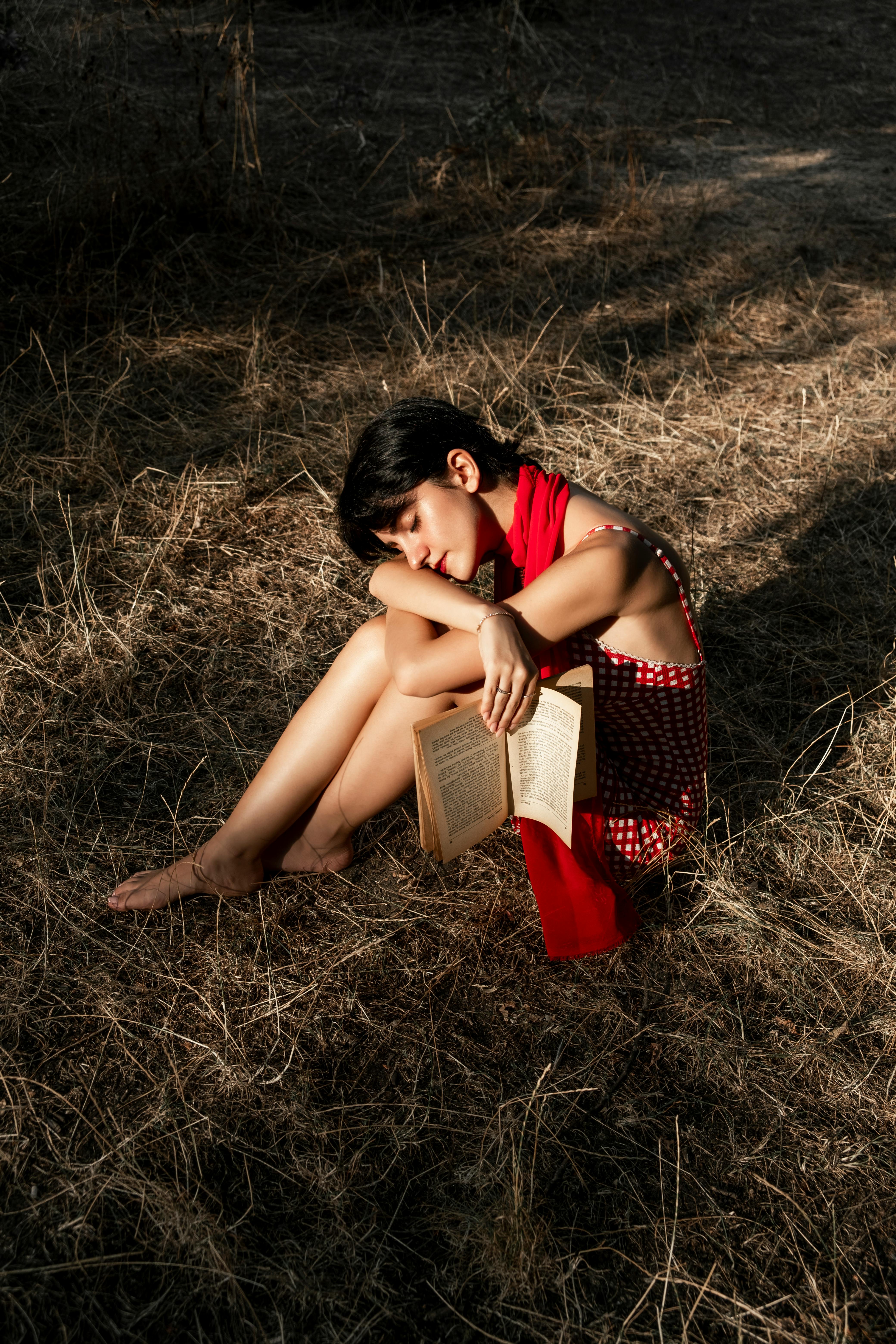 Woman relaxing in a field of grass, enjoying a quiet moment with a book.