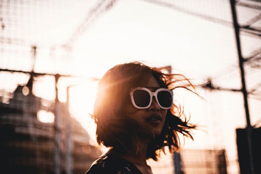 Chic woman wearing sunglasses posing outdoors at sunset in urban Vietnam.