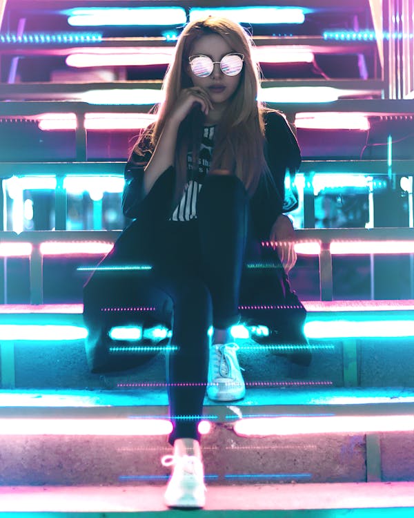 Woman Wearing Black and  Sunglasses Sitting Near Led Lights