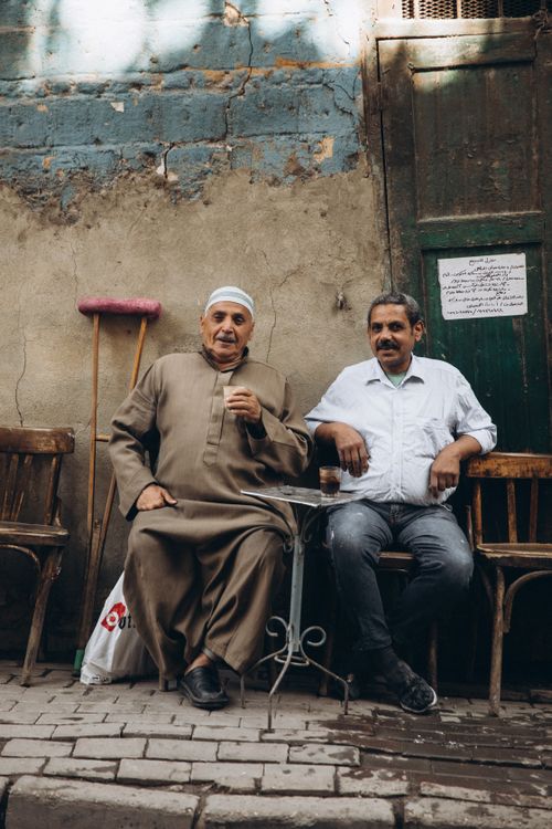 Free Two men sitting on a street in Cairo, showcasing local culture and lifestyle. Stock Photo