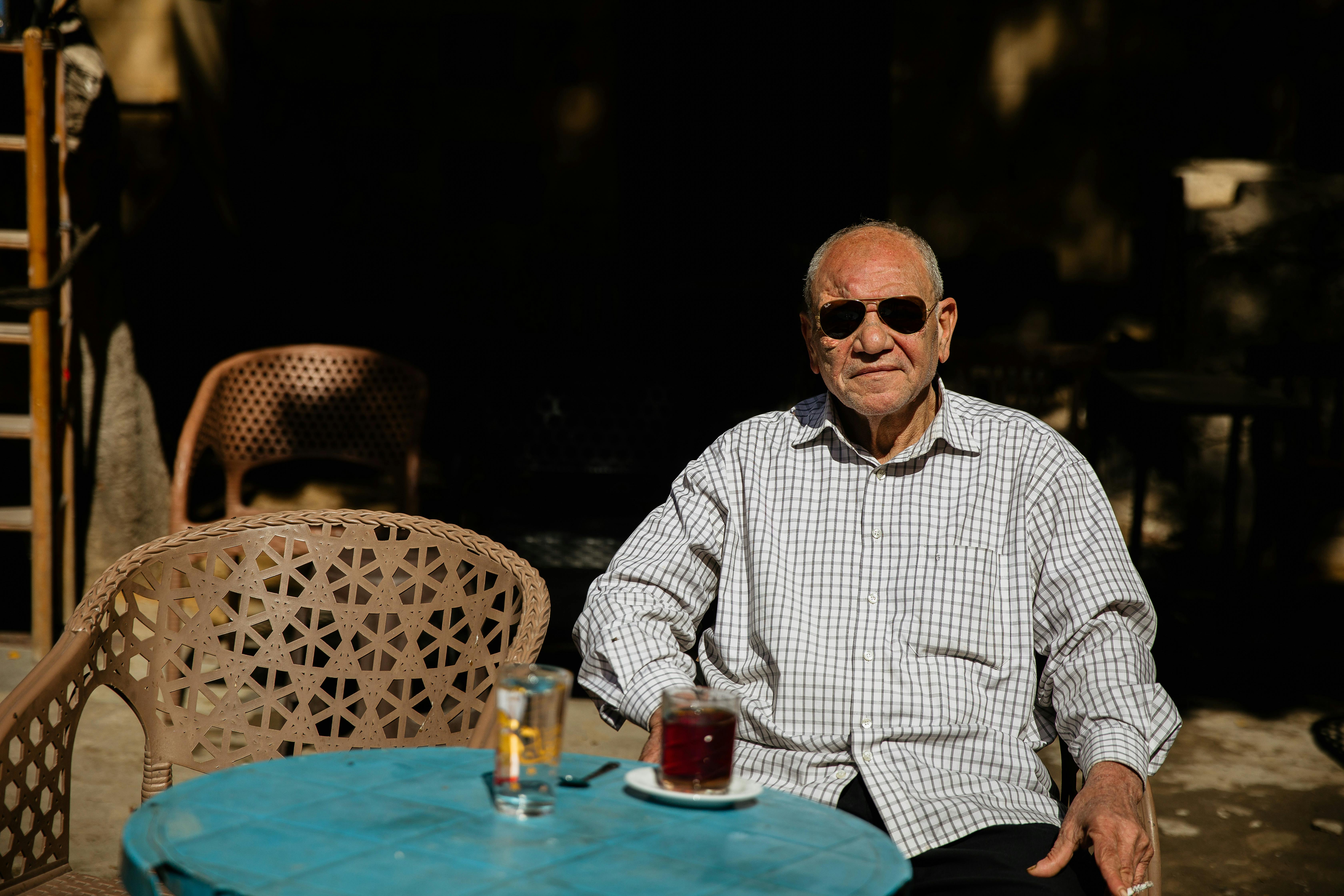 Elderly man with sunglasses sitting at an outdoor café table in Cairo, Egypt.