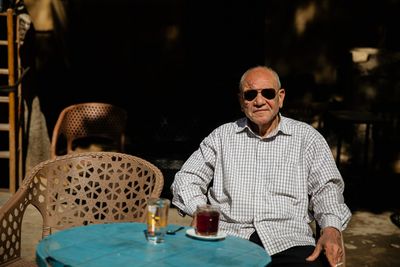 Elderly man with sunglasses at an outdoor café table in Cairo