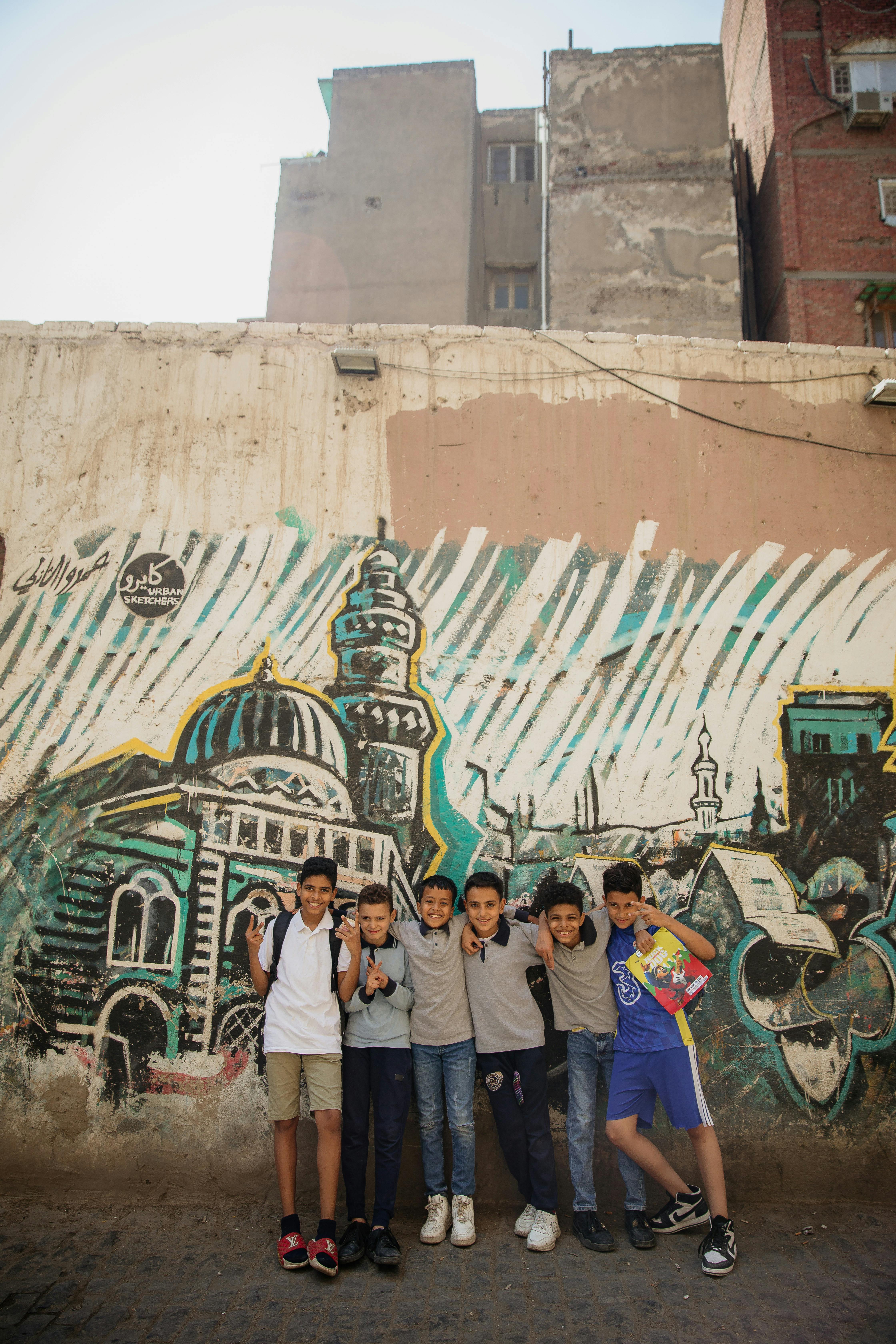 a group of boys standing in front of a graffiti wall