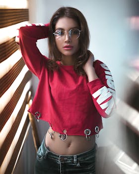 Fashionable woman posing confidently in a red crop top with unique design, wearing sunglasses