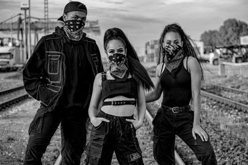 Free Black and white photo of a trio in urban streetwear with bandanas posing on train tracks. Stock Photo