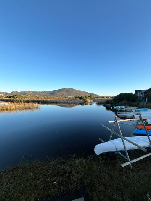 Free Tranquil morning scene of Lake Michelle in Cape Town, showcasing calm waters and distant mountains. Stock Photo