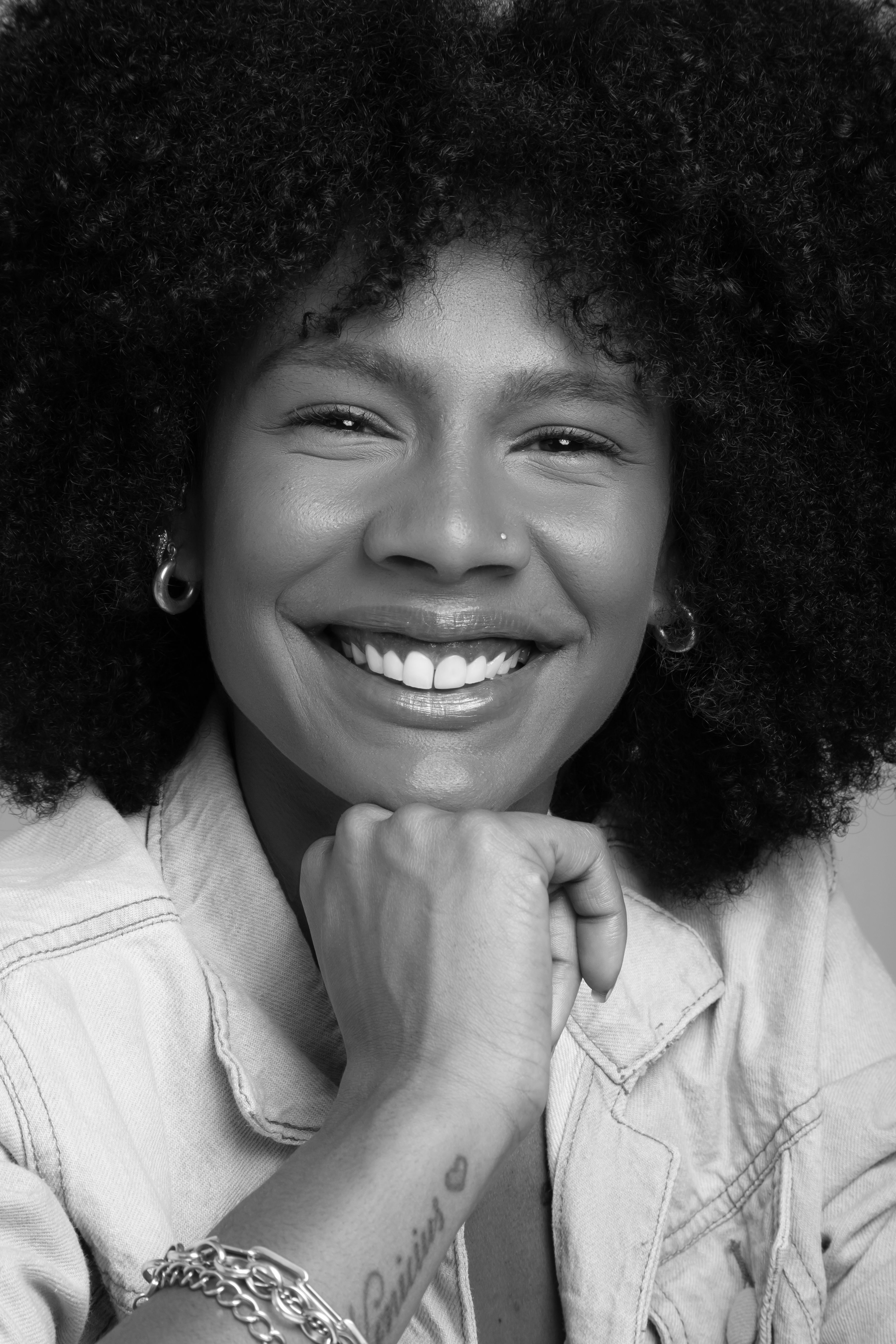 Captivating black and white portrait of a smiling woman with an afro hairstyle showcasing joy and personality.
