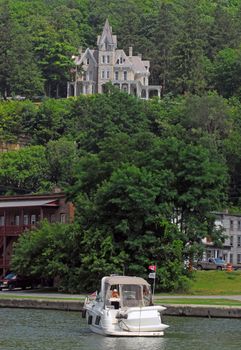 Charming historic mansion atop a hill, overlooking a serene river with lush greenery.
