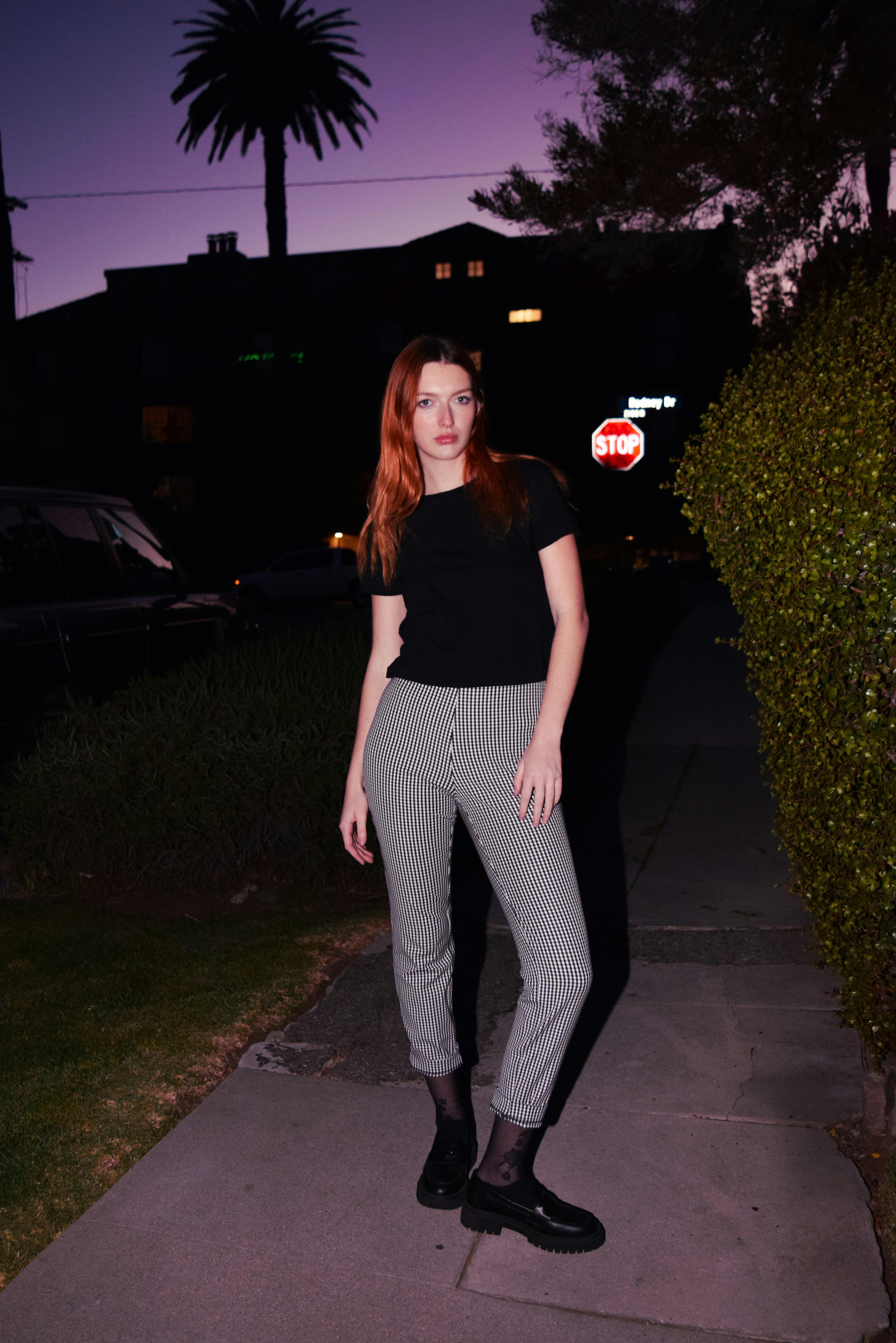 a woman in black shirt and pants standing on a sidewalk