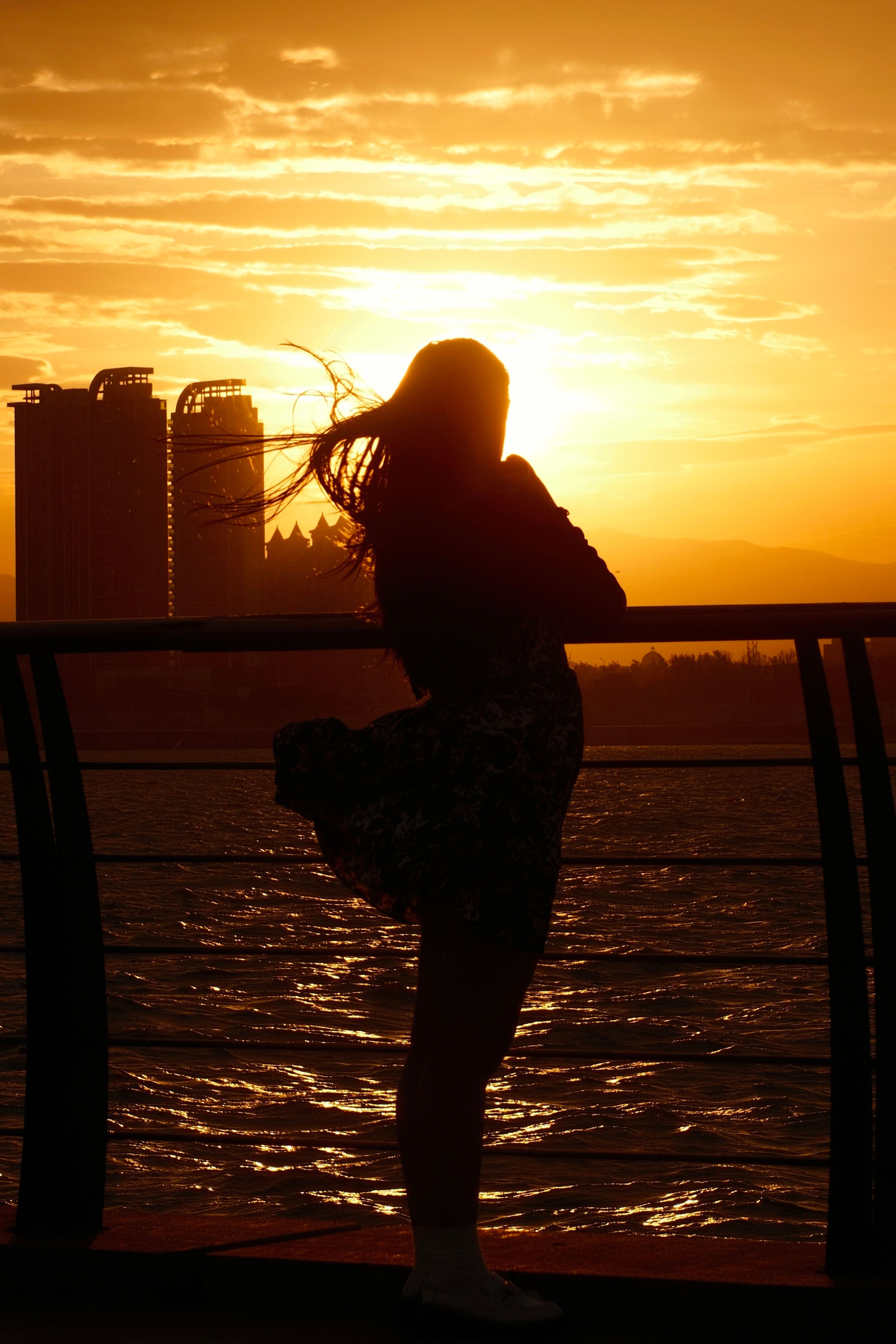 A woman standing on a pier at sunset · Free Stock Photo