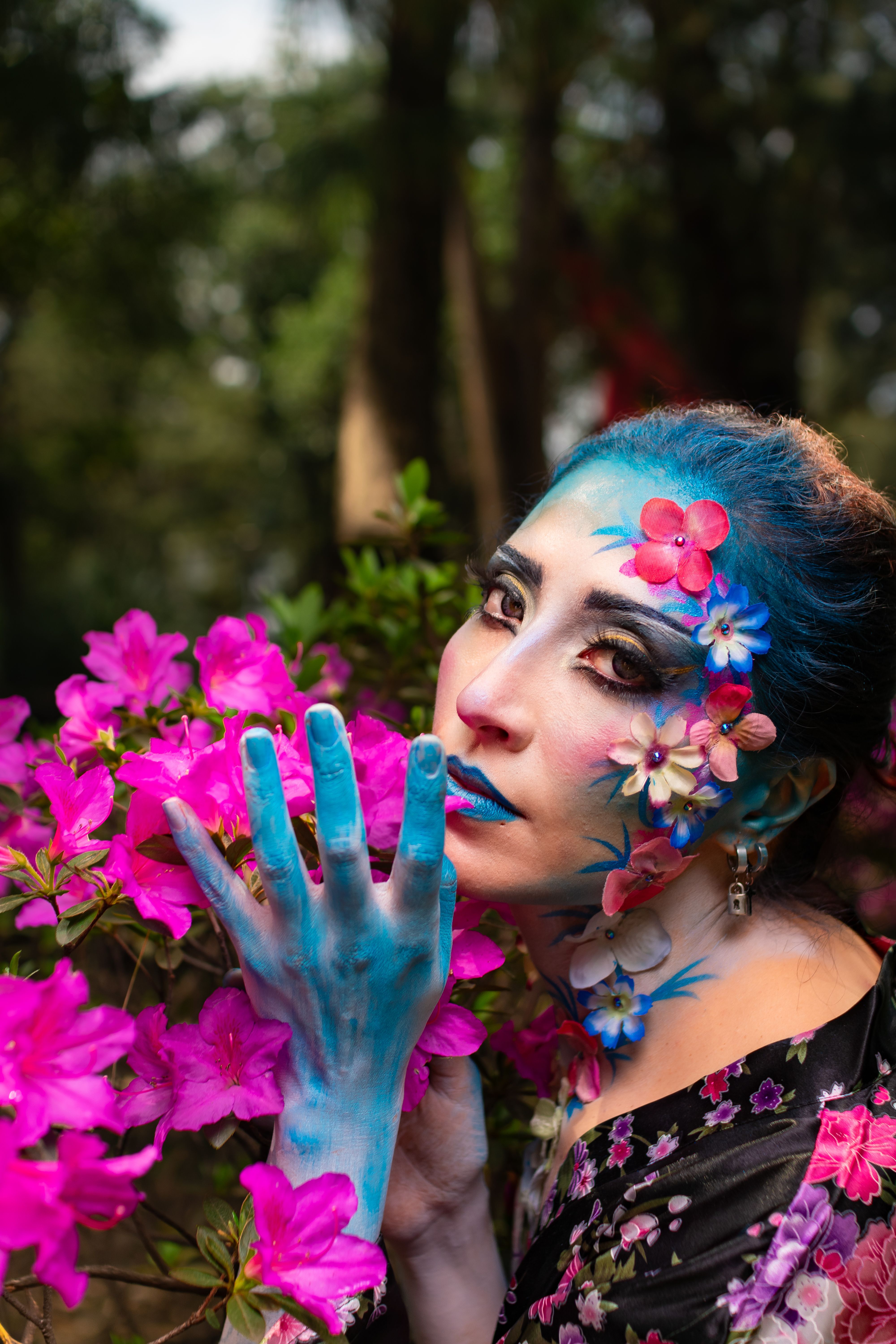A woman with blue face paint and flowers on her hands · Free Stock Photo