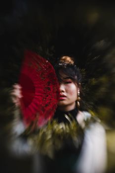 在吉隆坡，一名年轻女子手持红扇，优雅地摆出姿势