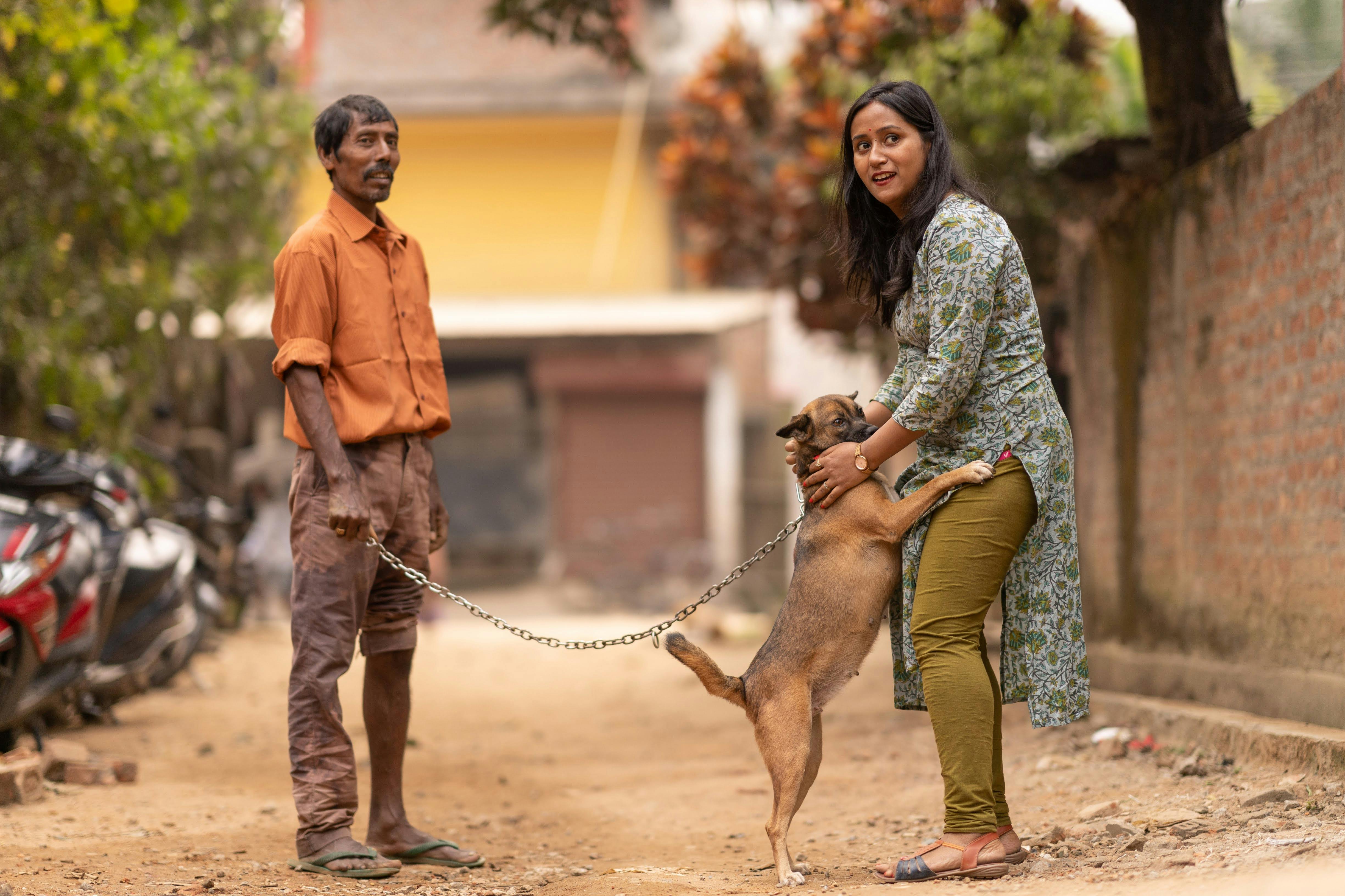 A man and woman standing next to a dog