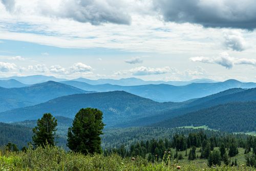 Free Serene view of lush mountains and forests under a dramatic sky, perfect for adventure and travel enthusiasts. Stock Photo