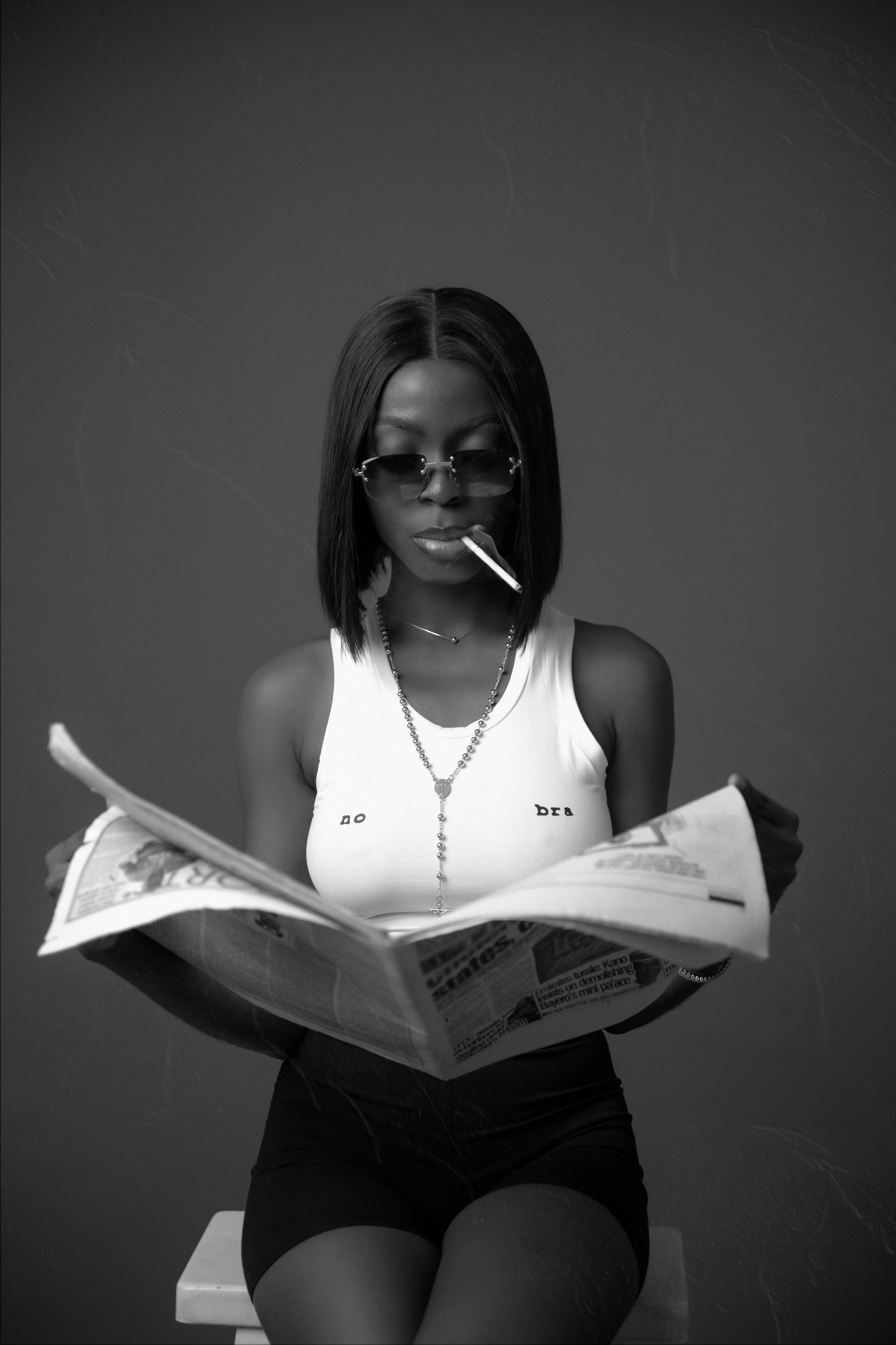 a woman reading a newspaper while smoking a cigarette