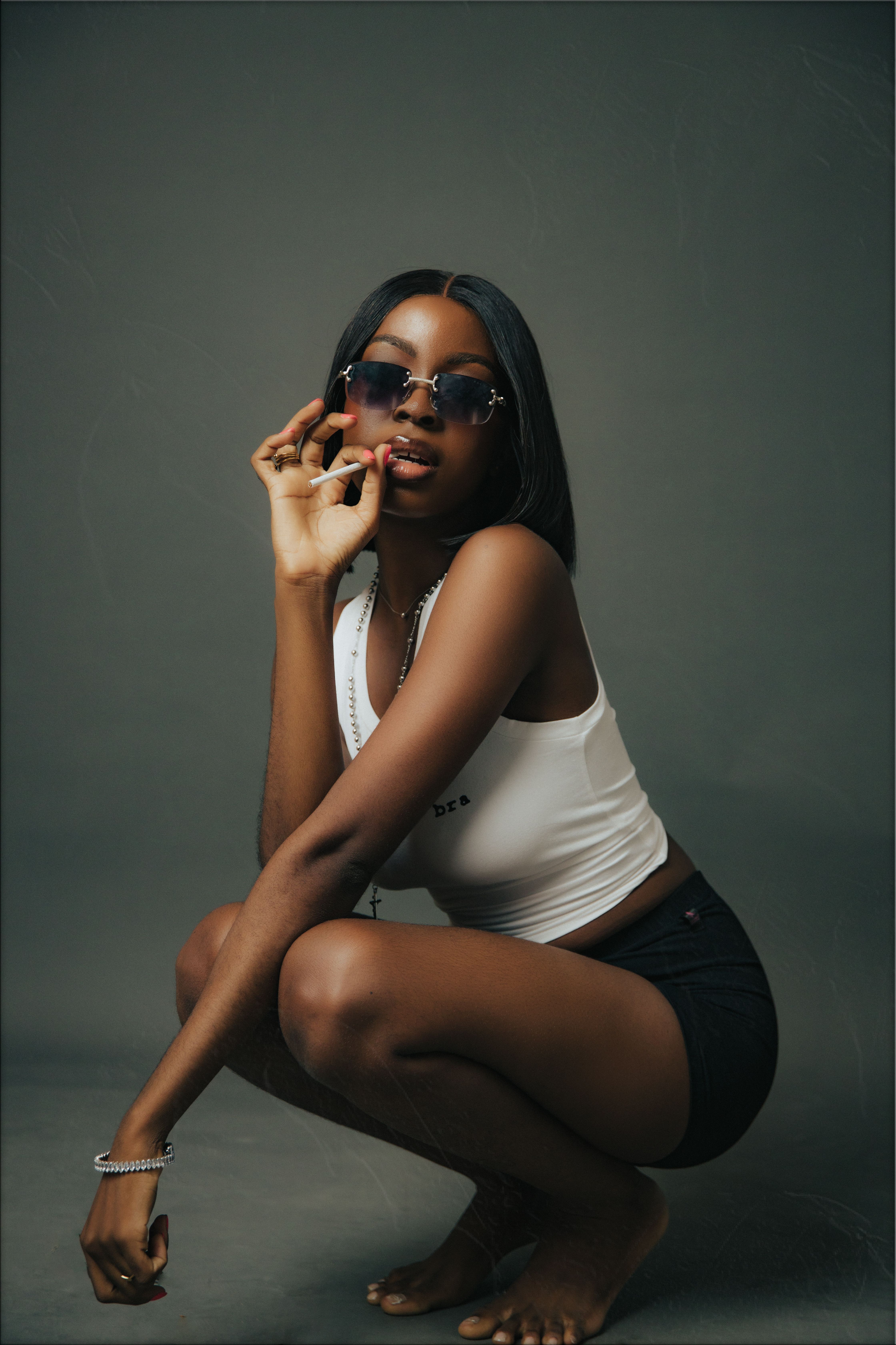 Studio Portrait of a Female Model Crouching with a Cigarette in Hand ...