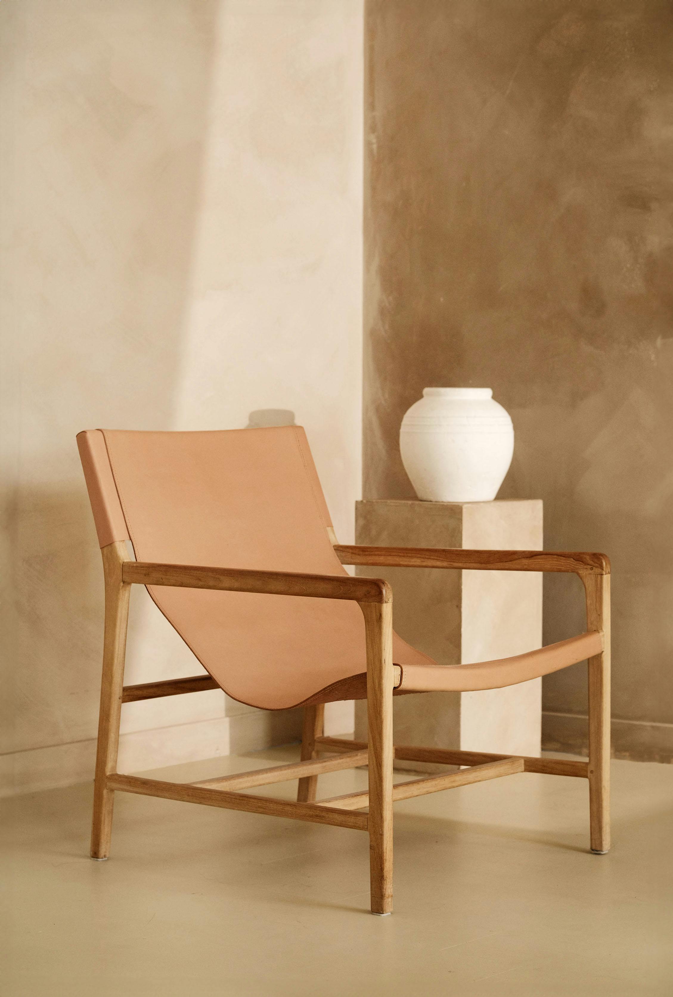 A cozy minimalist room with an armchair and white vase in neutral tones.