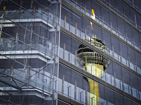 电视塔倒映在现代摩天大楼的玻璃立面上，呈现低角度透视