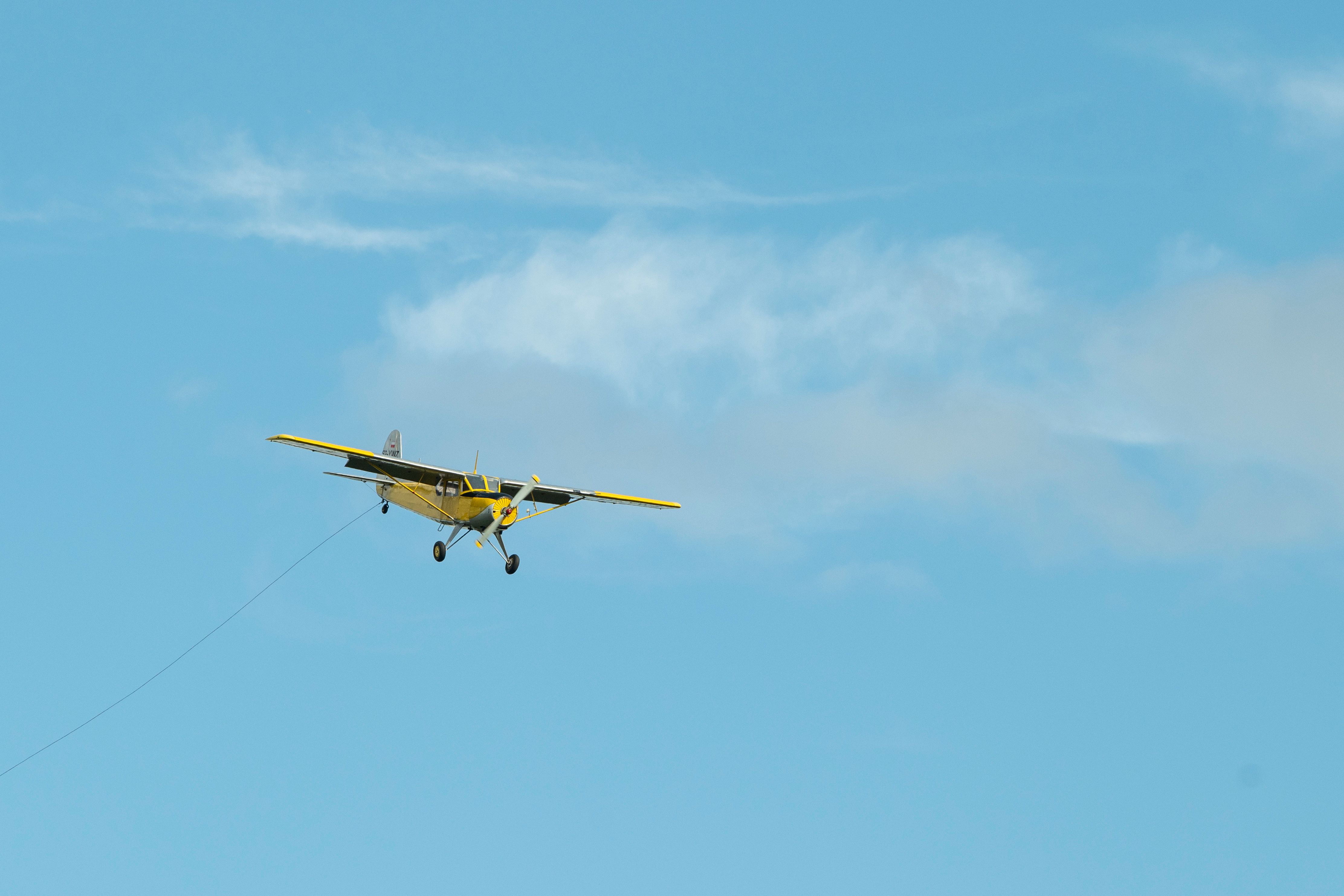 A yellow airplane flies against a clear blue sky, showcasing aviation and travel.