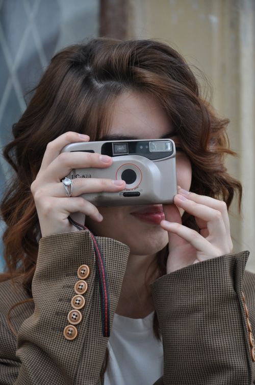 Free Young woman with vintage film camera outdoors, capturing candid moments. Stock Photo