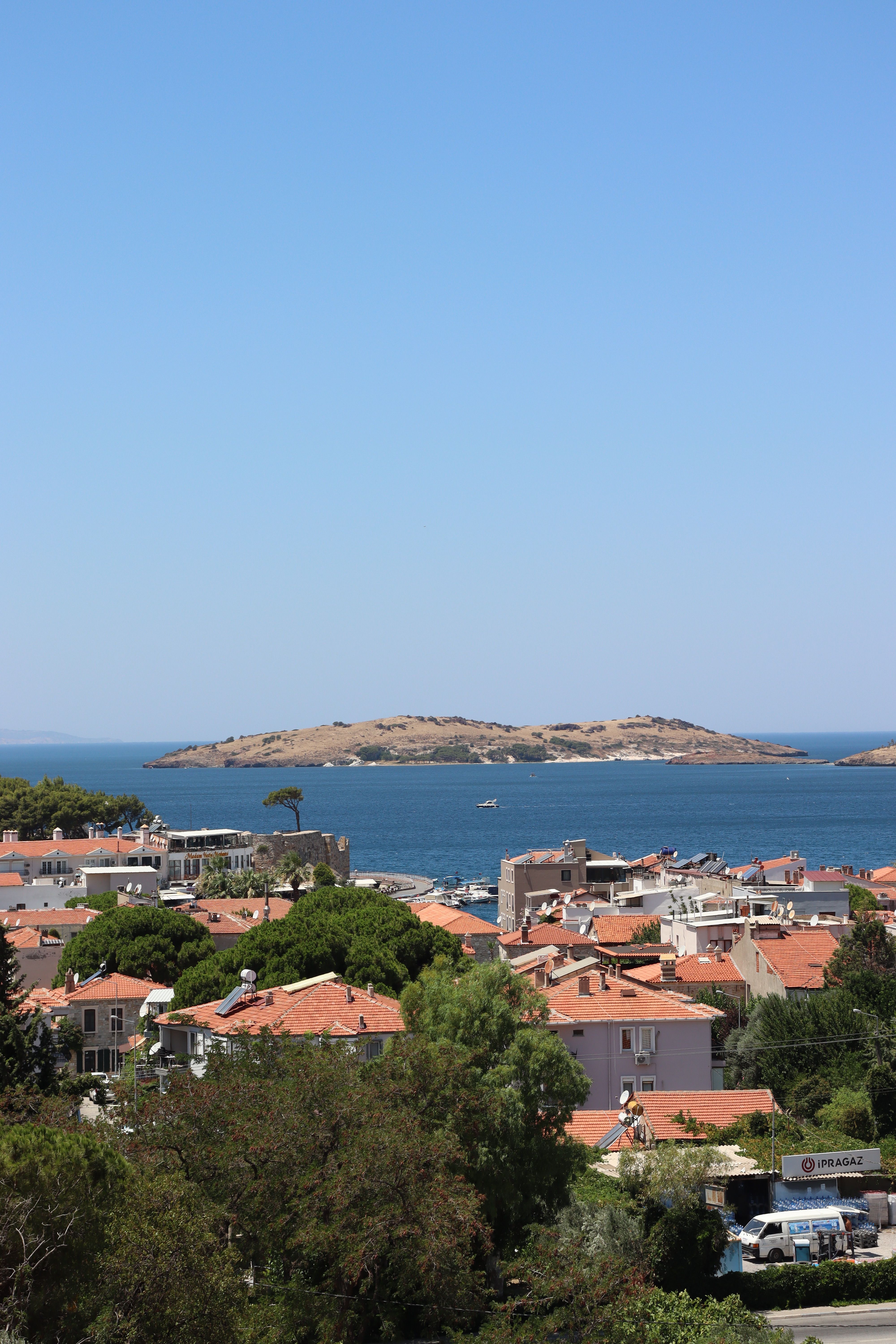 Charming coastal town with red roofs facing the tranquil sea and distant islands.
