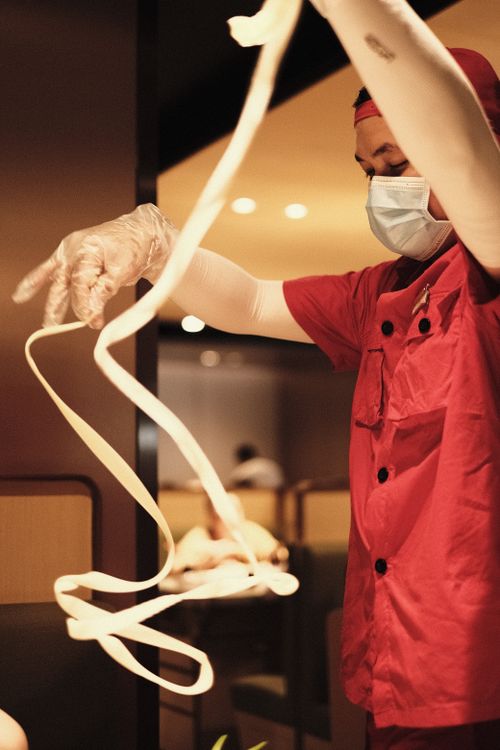 Free Chef skillfully stretches handmade noodles in a restaurant kitchen. Stock Photo
