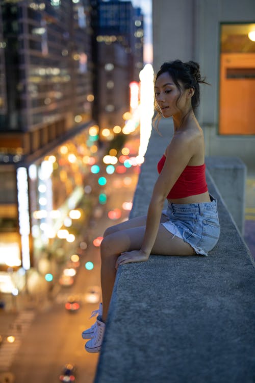 Woman Sitting On The Ledge Of A Rooftop