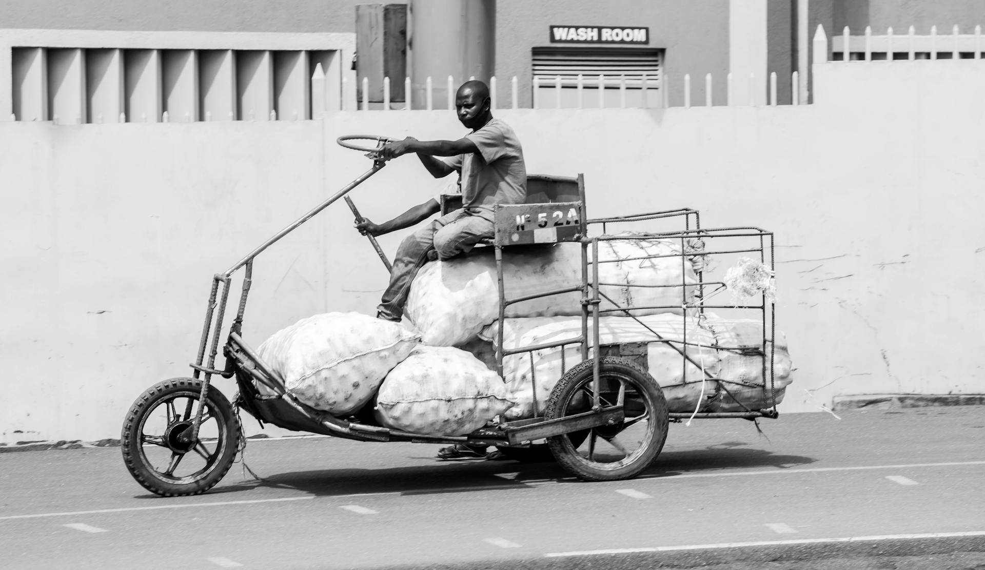 A man on a tricycle with a load of bags