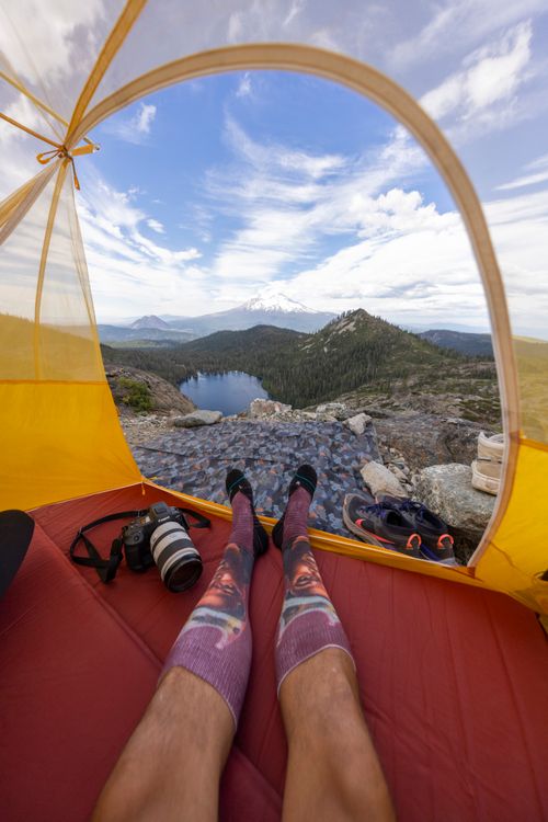 Free Experience a breathtaking mountain landscape from a cozy tent with camping gear. Stock Photo