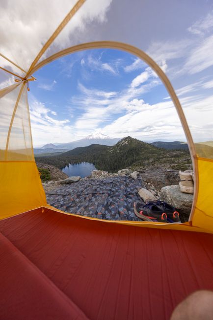 A cozy sleeping bag laid out on a camping pad inside a tent with a lantern glow
