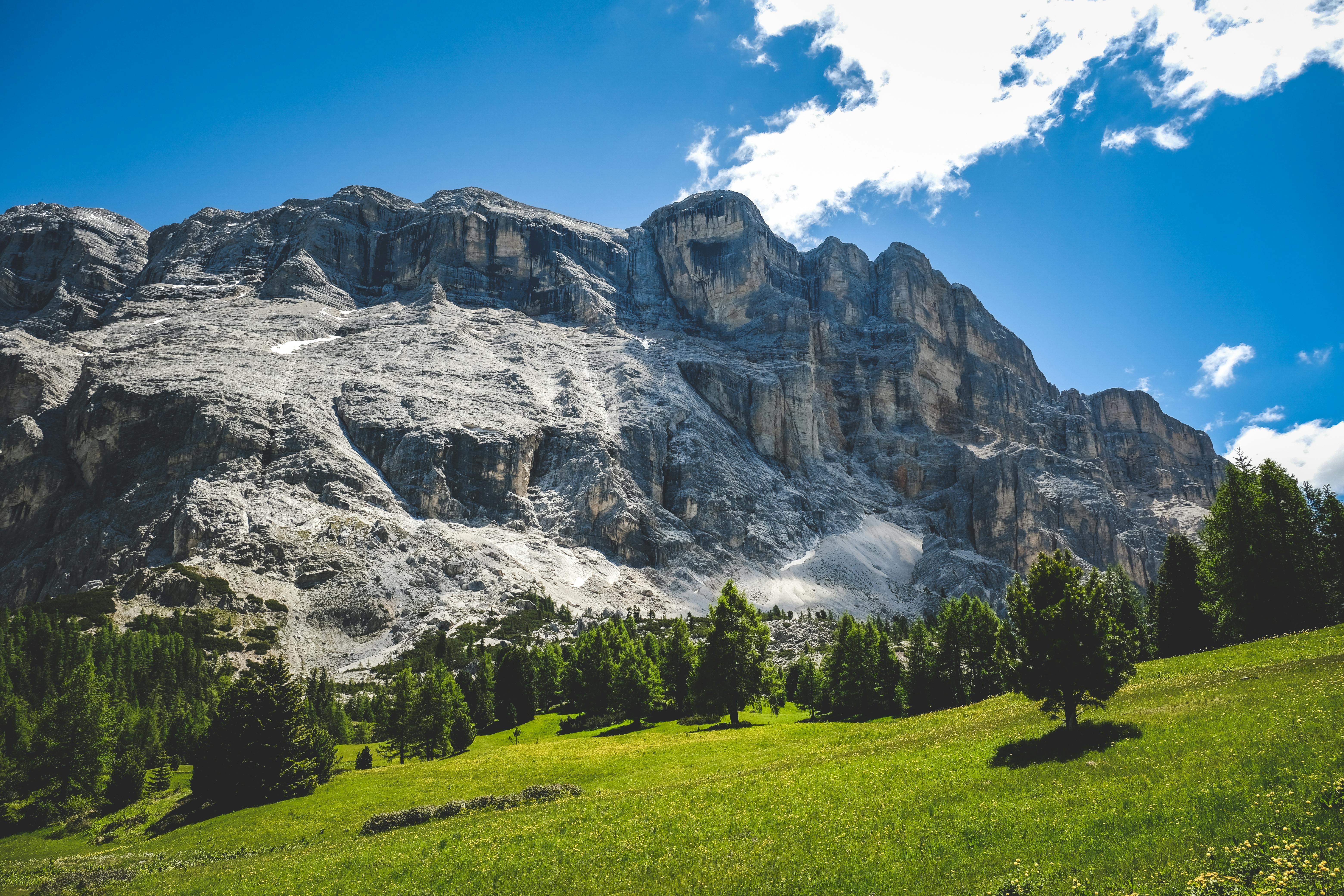 a mountain with a green grassy field and blue sky