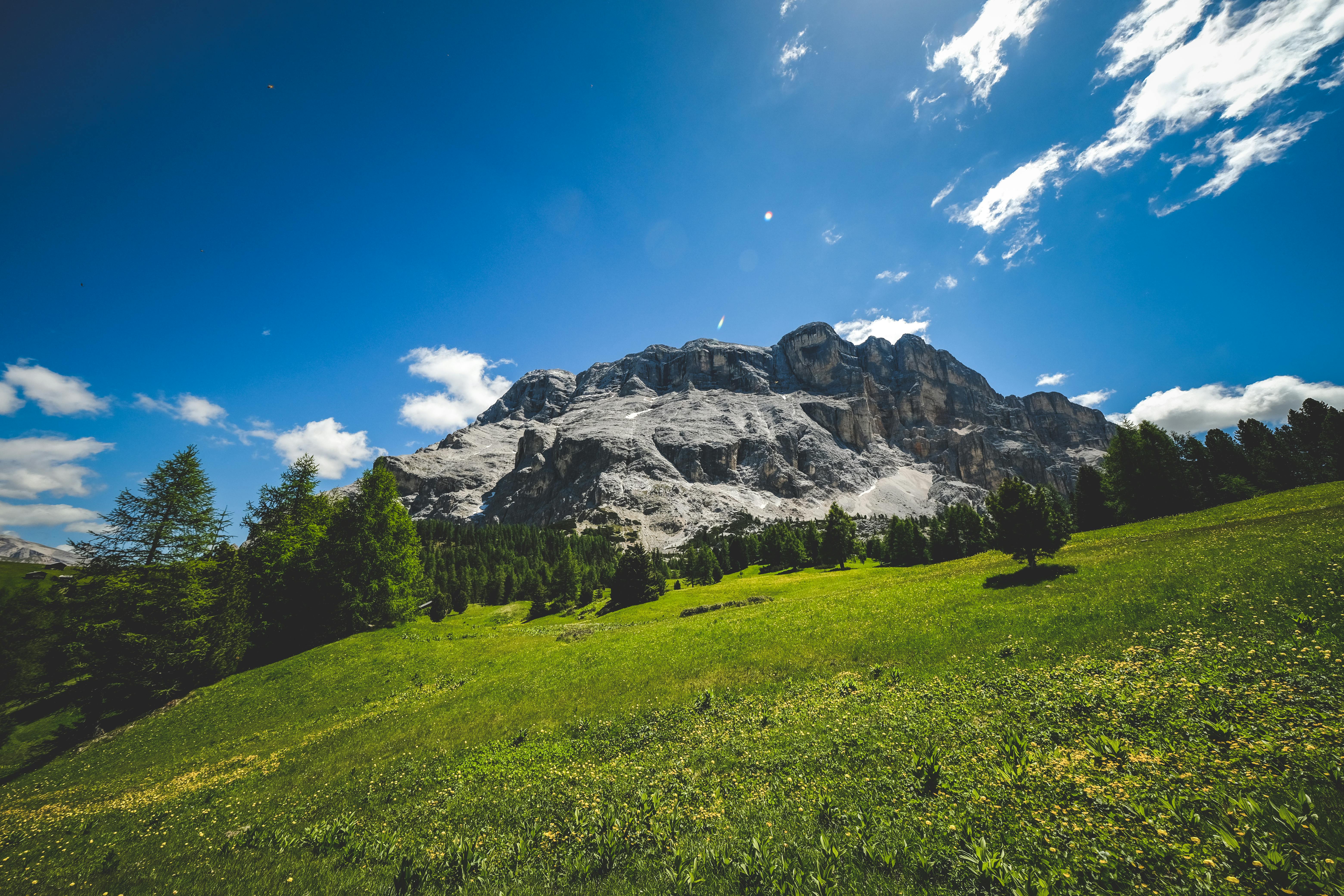 A grassy hill with a mountain in the background · Free Stock Photo