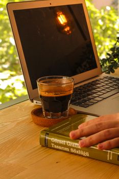 A warm, relaxed workspace featuring a laptop, coffee, and book on a wooden table.